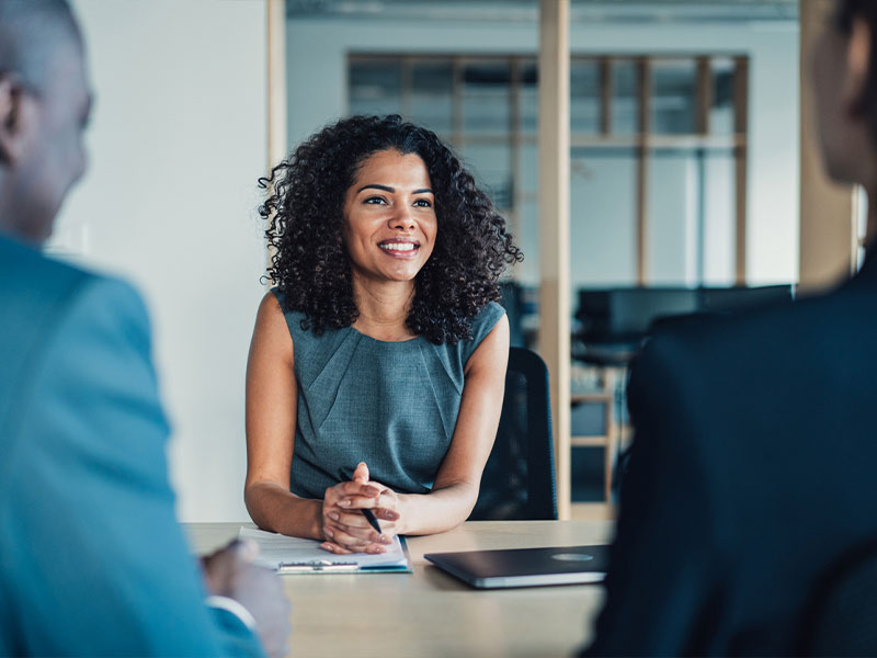 A woman smiling during a business meeting in an office setting.