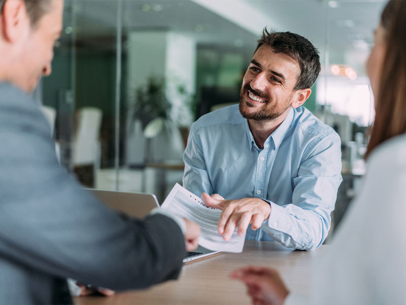 Man in a light blue shirt discussing documents at a business meeting.