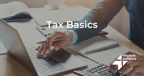 Person working on laptop and calculator with 'Tax Basics' text overlay.