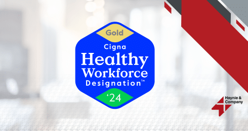 Gold Cigna Healthy Workforce Designation 2024 badge with Haynie logo on a blurred background.