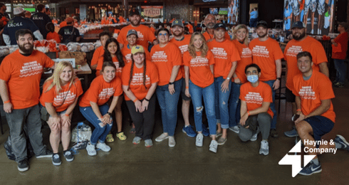 Group of people in matching orange shirts at a Haynie event inside a restaurant setting.