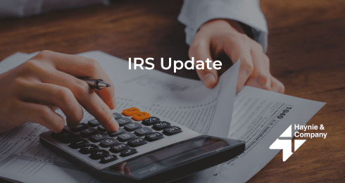 Hands using calculator and reviewing IRS update documents.