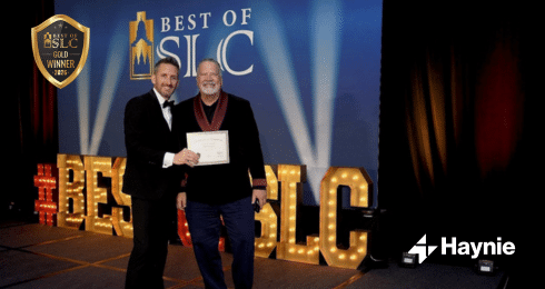 Two men smiling, one holding a certificate, at the Best of SLC awards event.