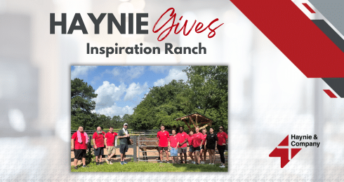 Haynie team at Inspiration Ranch event, wearing red shirts, standing in a field with trees in the background.