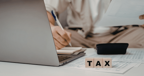Person working on taxes with a laptop and documents on a desk.