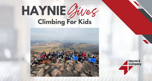 Group on a mountain, part of Haynie Gives Climbing for Kids event, bright day with distant landscape view.