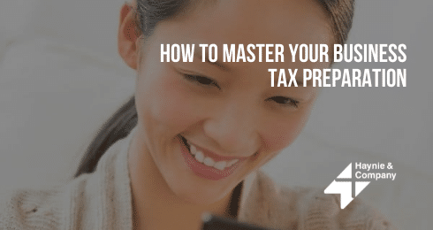 Smiling woman reading phone, text overlay How to Master Your Business Tax Preparation, Haynie logo.