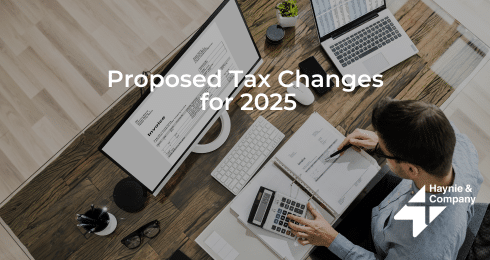 Man reviewing documents on tax changes for 2025 at a desk with a computer.