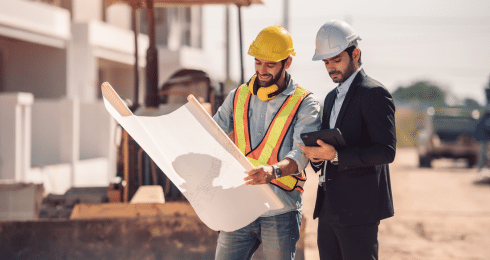 Construction workers reviewing blueprints at a job site.