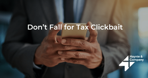 A person in a suit holding a smartphone, overlaid with Don't Fall for Tax Clickbait and Haynie logo.