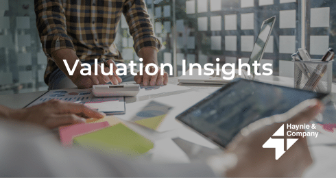 People working at a table with documents and a tablet, text: Valuation Insights, Haynie logo visible.