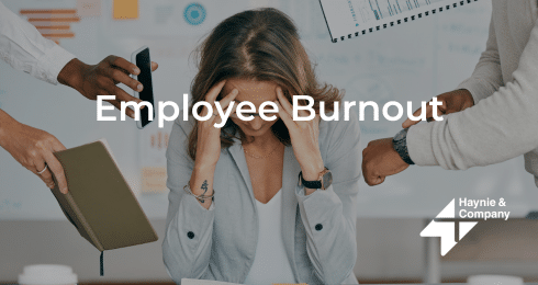 A stressed woman surrounded by colleagues highlighting employee burnout.