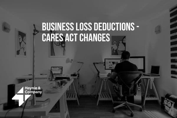 Business Loss Deductions - Cares Act Changes text in a home office setting with a person at a desk.