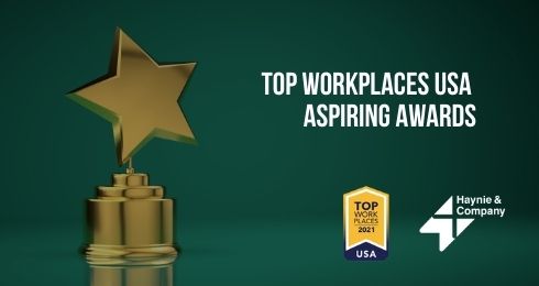 Gold star award with Top Workplaces USA Aspiring Awards text and Haynie logo on green background.