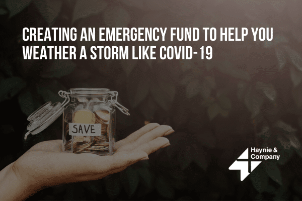 Creating emergency fund; hand holds jar with coins labeled 'SAVE' against dark leafy background.