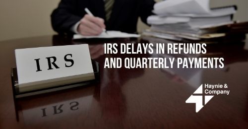 IRS office desk with a sign, documents, and text about refund and payment delays.