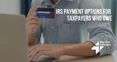 IRS payment options text with person holding a credit card and using a laptop.
