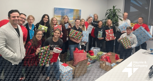 Group of people at Haynie holding wrapped gifts in an office setting.