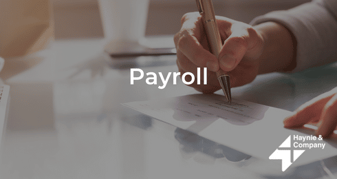 Hand writing on a check with Payroll text and Haynie logo.