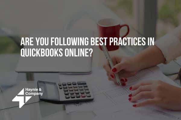 Person using calculator and reviewing documents; text: Are You Following Best Practices in QuickBooks Online?