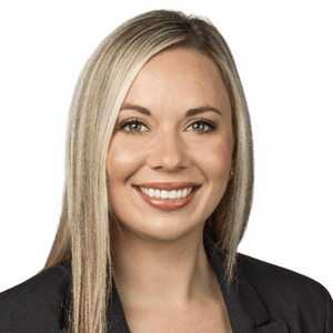 A smiling woman with long blonde hair in professional attire against a white background.
