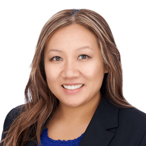 Woman smiling in a professional headshot, wearing a black blazer and blue top, on a white background.