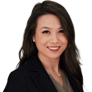 A professional woman smiling in a business suit, with long hair and a white background.