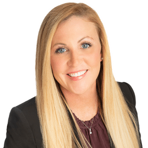 A woman with long blonde hair smiling in business attire.