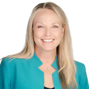 A smiling woman in a teal blazer against a white background.