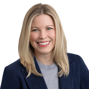 A woman smiling in a blue blazer against a white background.