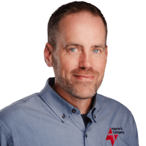 Man in embroidered business shirt smiling against white background.