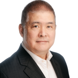 A man in a suit with a neutral expression against a white background.