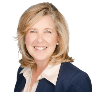 A smiling woman with blonde hair wearing a navy blazer and a white shirt.