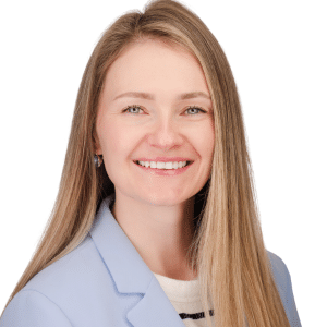 A smiling woman with long blonde hair in a light blue blazer against a white background.