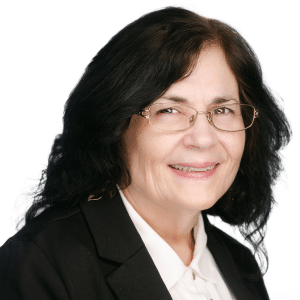 A woman with glasses smiling and wearing a business suit against a white background.