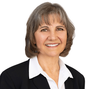 A professional woman smiling in business attire against a plain background.