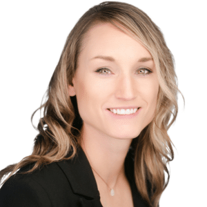 A woman with wavy blonde hair smiling in a black blazer against a white background.