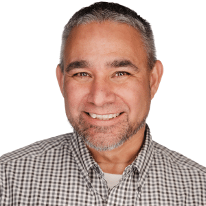 A man smiling in a checkered shirt against a white background.
