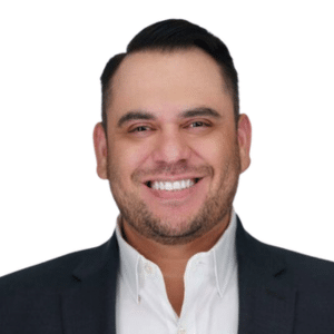 A man smiling in a suit and white shirt on a white background.