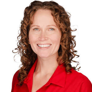 A woman with curly hair in a red shirt smiling at the camera.
