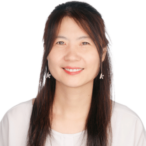 A woman with long hair smiling against a plain white background.