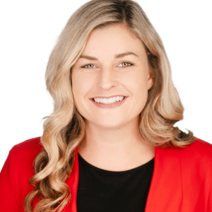 A smiling woman with long blonde hair in a red blazer against a white background.