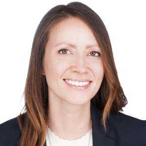 Smiling woman with brown hair in professional attire against a white background.