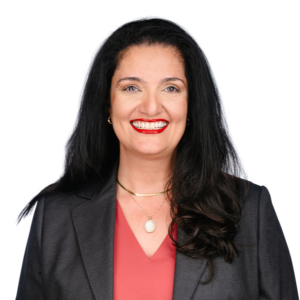 A woman in a blazer with long dark hair and a bright smile against a white background.