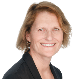 A smiling woman with short hair in a black blazer against a white background.