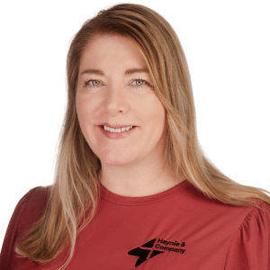 A woman in a red Haynie shirt, smiling against a white background.