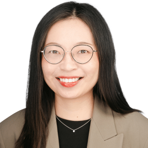 A woman wearing glasses and a brown blazer smiles in a professional headshot.