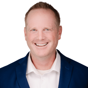 A smiling man in a blue suit and white shirt on a white background.