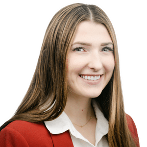 A woman smiling in a red blazer with a white background.