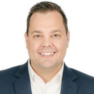 A man in a suit smiling against a white background.